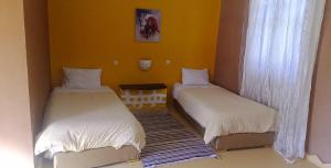 two beds in a room with yellow walls at AUBERGE DES ANGES in Zrigat +5 photos