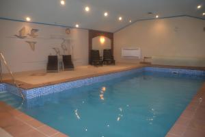 a large swimming pool in a room with chairs and a table at Ferienhaus Auszeit am See in Walchum