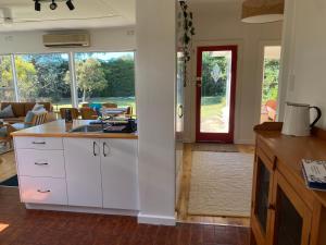a kitchen with white cabinets and a living room at WattleJack Cottage in Kingscote