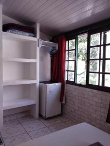 a kitchen with a refrigerator in a room with windows at Canto da Arte - Hospedagem Domiciliar in Cabo Frio