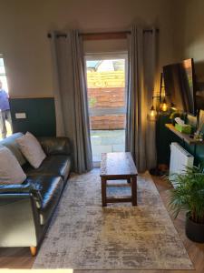 a living room with a leather couch and a coffee table at The Hide in Ullapool