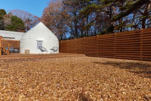 a white barn with two chairs in front of a fence at ReSchool Nasu Glamp in Nasu