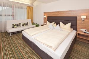 1 dormitorio grande con 1 cama grande y 1 sofá en Akzent Hotel Höhenblick, en Mühlhausen im Täle