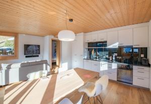 a kitchen with white cabinets and a wooden ceiling at Chalet Sterndolde Apt 1 in Wengen +19 photos