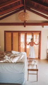 a woman standing in a bedroom looking out the window at Canto dos Pireneus Hospedaria in Pirenópolis