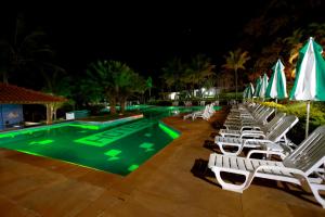 a pool with lawn chairs and umbrellas at night at Hotel Berro D`Agua Eco Resort in Avaré
