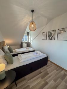 a bedroom with two beds and a chandelier at C4S COME4STAY Altötting - 3-Zi Whg I Zentrale Lage I Parkplatz I Balkon I WIFI I SmartTV I 1 Kingsize, 1 Queensize Bett I Office Arbeitsplatz I Wohnbereich mit Couch und Essbereich I voll ausgestattete Küche I Nespresso in Altötting
