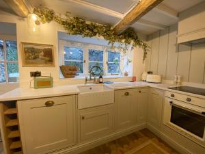 a kitchen with white cabinets and a sink at The Cottage on the Island in Castleton
