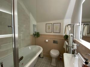 a bathroom with a tub and a toilet and a sink at The Cottage on the Island in Castleton