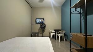 a bedroom with a bed and a table and a tv at Suíte 03 • Praia das Pitangueiras in Guarujá