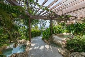 a garden with a swimming pool and a wooden pergola at Bougainvillea Barbados in Christ Church