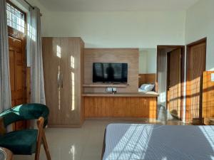 ein Wohnzimmer mit einem TV und ein Zimmer mit einem Bett in der Unterkunft Hues & Trails Ground Zero in Shimla