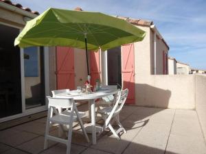 une table avec deux chaises et un parasol vert dans l'établissement SP480-153 Maison 3 pièces SAINT PIERRE LA MER, à Saint Pierre La Mer