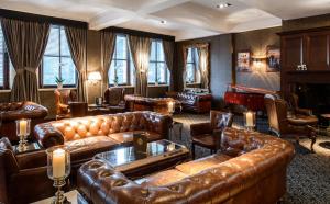 a living room with leather couches and a piano at The Vermont Hotel & Vermont Aparthotel in Newcastle upon Tyne