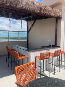 a bar with chairs and a counter with a view of the ocean at Flat - Eco Miragem Centro de Porto de Galinhas in Porto De Galinhas