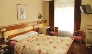 盧森堡的住宿－蘇黎世酒店，一间卧室配有一张带两把椅子的床和一扇窗户