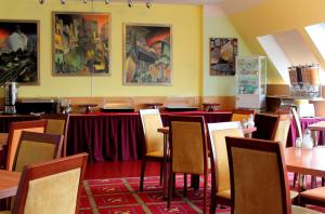 un comedor con mesas, sillas y pinturas en la pared en Hotel Kaiser, en Berlín