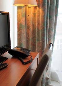 a desk with a laptop and a monitor on it at Hotel Kaiser in Berlin