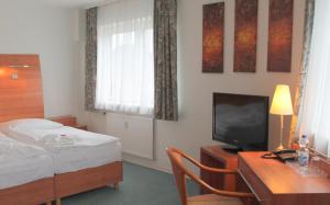 a hotel room with a bed and a desk with a television at Hotel Kaiser in Berlin