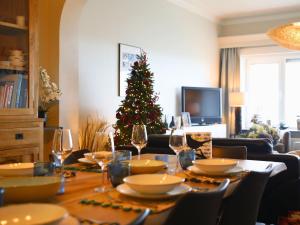 una mesa de comedor con copas de vino y un árbol de Navidad en SeaSide Rendez-vous - Appartement 3 chambres Vue mer, piscine, sauna & parking à Middelkerke, en Middelkerke