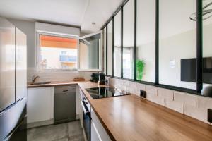 a kitchen with white walls and wooden counters and windows at 123home - Suite & spa XL in Montévrain
