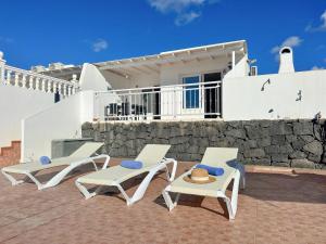 2 weiße Stühle, ein Tisch und ein Gebäude in der Unterkunft Villa Siempre Mar in Puerto del Carmen