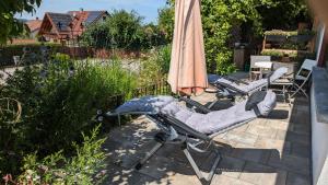 three lounge chairs and an umbrella on a patio at Landmanns Home in Pottenstein