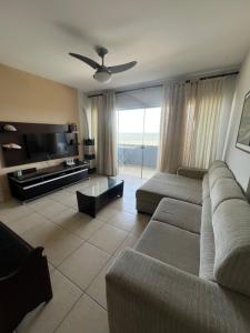 a living room with a couch and a flat screen tv at Pé na areia incrível in Piçarras