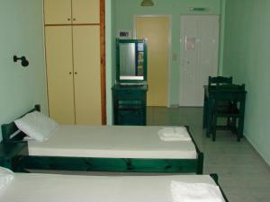 1 dormitorio con 2 camas y TV. en Ferouli Residence, en Rizá