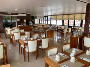 a restaurant with wooden tables and chairs and a kitchen at Hotel Mare in Nazaré