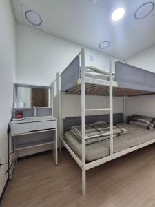 a bedroom with two bunk beds and a desk at All Stay Hostel in Seoul