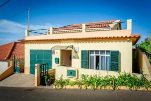 ein weißes Haus mit grünen Türen und einem Tor in der Unterkunft Home Thomas in Lombada dos Marinheiros