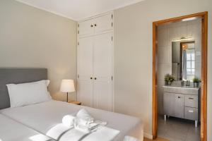 a bedroom with a white bed and a bathroom at Canaan Boutique Casa do Monte by Get Your Stay in Boliqueime