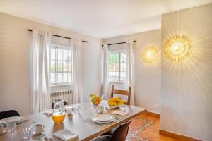 a dining room with a table and two windows at Canaan Boutique Casa do Monte by Get Your Stay in Boliqueime
