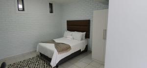 a bedroom with a bed in a white brick wall at Grace Villas 25 in East London