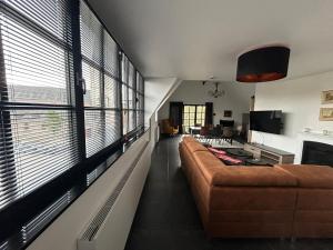 Una sala de estar con un sofá y algunas ventanas. en La Forteresse, en Borgloon