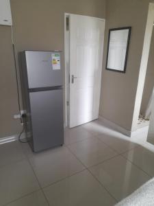 an empty room with a refrigerator and a door at Park Q Residence in Pimville