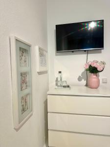 a room with a dresser with a tv on a wall at FRIDA Hannover City Apartment&Privatzimmer in Hannover