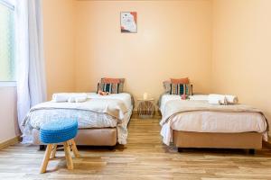 ein Zimmer mit zwei Betten und einem Hocker in der Unterkunft Home Thomas in Lombada dos Marinheiros