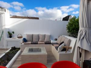 a patio with a couch and a table and chairs at O Aconchegadinho in Rabo de Peixe
