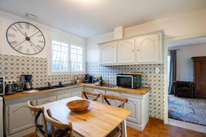 a kitchen with a table and a clock on the wall at La Villa Cyrano - Maison avec piscine privée! in Bergerac