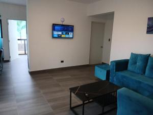 Villa Rivaにあるaparthotel las taranasのリビングルーム(青いソファ、壁掛けテレビ付)