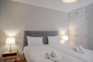a bedroom with a large white bed with two slippers at Canaan Boutique Casa do Monte by Get Your Stay in Boliqueime