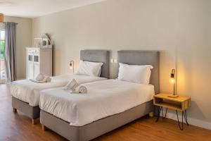 two twin beds in a bedroom with a night stand at Canaan Boutique Casa do Monte by Get Your Stay in Boliqueime