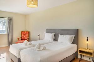 a bedroom with two beds with white sheets and a chair at Canaan Boutique Casa do Monte by Get Your Stay in Boliqueime