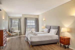 a bedroom with a bed and a dresser and two windows at Canaan Boutique Casa do Monte by Get Your Stay in Boliqueime