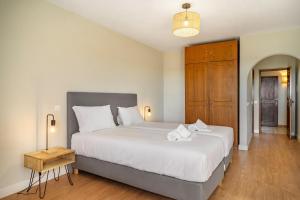 a bedroom with a large white bed and a wooden floor at Canaan Boutique Casa do Monte by Get Your Stay in Boliqueime
