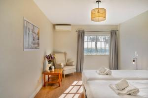 a bedroom with two beds and a chair and a window at Canaan Boutique Casa do Monte by Get Your Stay in Boliqueime +37 photos