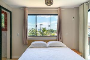 ein Schlafzimmer mit einem Bett und einem großen Fenster in der Unterkunft #PDS7 - (Refúgio e Mar) Hospedagem em Canto Grande, Bombinhas in Bombinhas