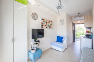 a living room with a tv and a blue chair at Coco cozy home in Pefkochori